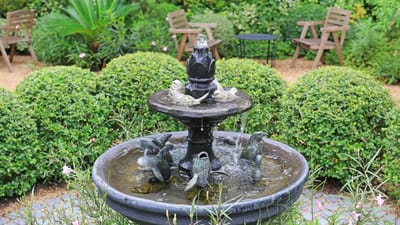 Garden fountain surrounded by greenery and seating.