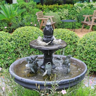 Outdoor fountain surrounded by greenery and seating.