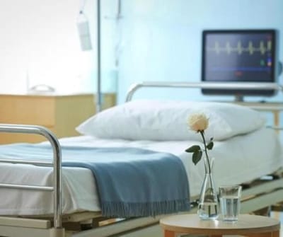 Hospital room with a bed, a flower, and a monitor.