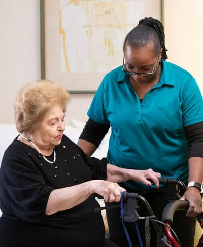 Caregiver assisting a resident with mobility aid