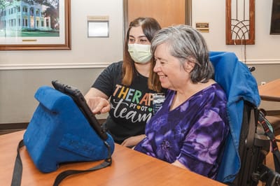 Staff member assisting resident with a tablet