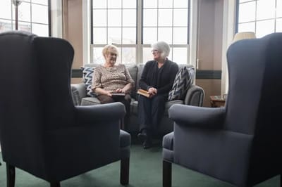 Two residents chatting in a cozy common area