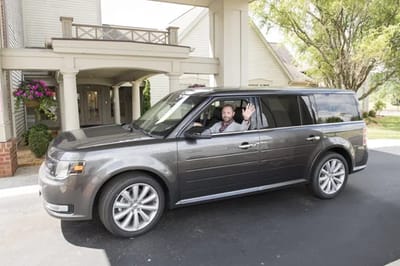 A man waving from a vehicle at the facility entrance