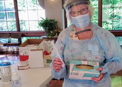 Staff member in personal protective equipment handling supplies