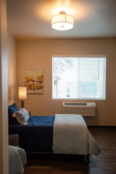 A well-furnished resident room with a bed and window