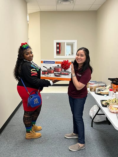 Two women holding a cookware set in a facility interior
