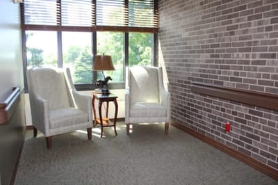 Cozy seating area with two chairs and a lamp by large windows