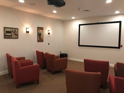 Cozy indoor theater with red chairs and a large screen