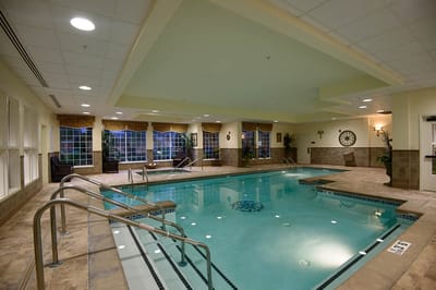 Indoor swimming pool area with lounge chairs and windows