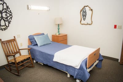 A cozy private resident room with a bed and rocking chair