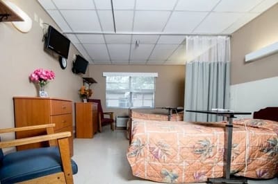 A shared resident room with two beds and a TV