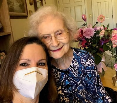 Staff member posing with a senior resident in a cozy room