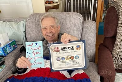 A resident holding a card and a certificate of recognition