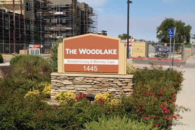 Sign of The Woodlake Senior Living facility with flowers