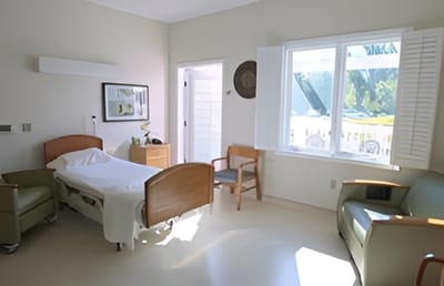Bright, airy private resident room with a bed and chair
