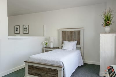 A well-furnished resident room with a bed and nightstand