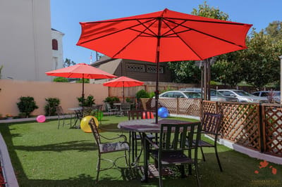 Outdoor seating area with red umbrellas and green lawn