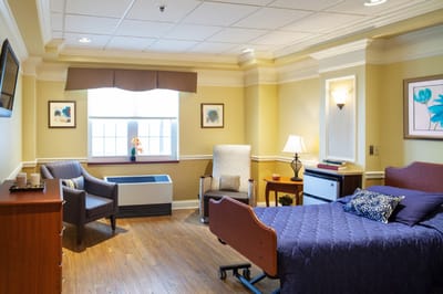 Cozy resident room with a bed, chair, and window