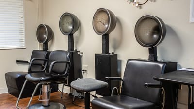 Hair salon area with styling chairs and dryers