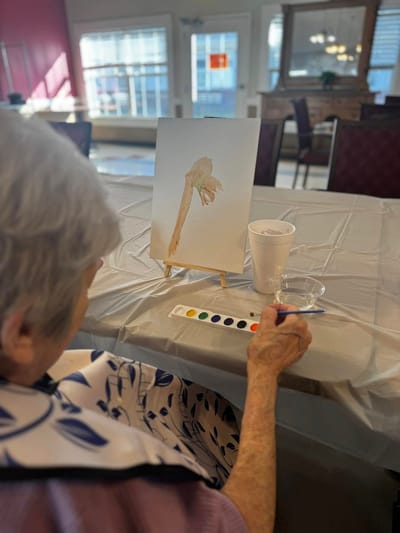 A resident painting in a common area during an art activity