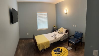 A private resident room with bed and chair