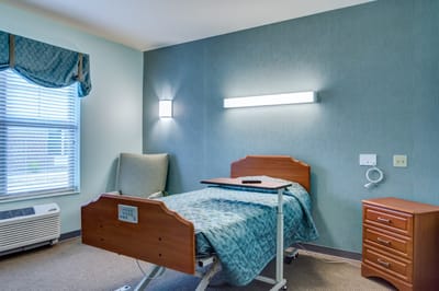 A well-furnished private resident room with a bed and chair