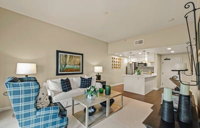 A bright, well-furnished living room in a senior facility unit.