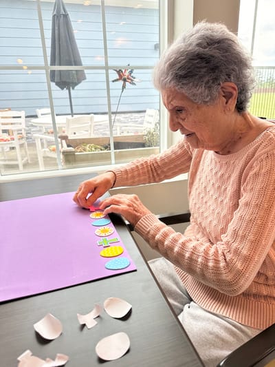 A resident crafting with colored paper at a table