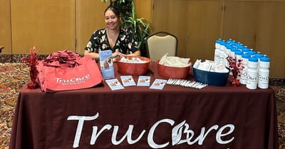 Staff member at TruCare booth with promotional materials