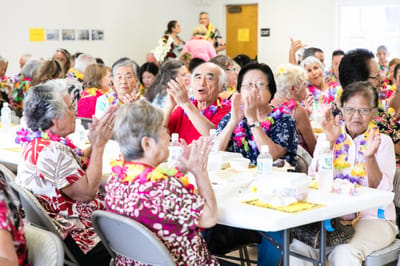 Residents celebrating with leis and food at a dining area