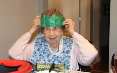 Elderly resident wearing a paper crown and smiling