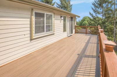 Deck area with wooden railing and trees in the background