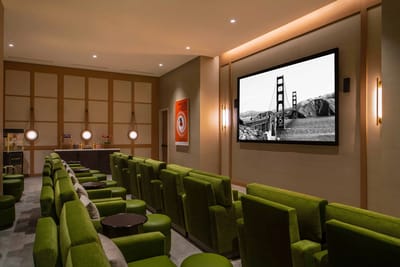 Interior seating area with green chairs and a large screen