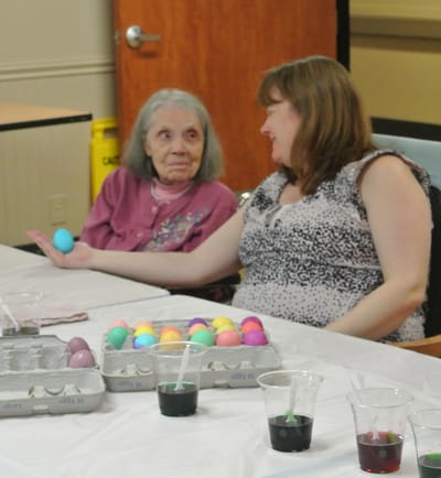 Residents and staff engaging in an egg decorating activity