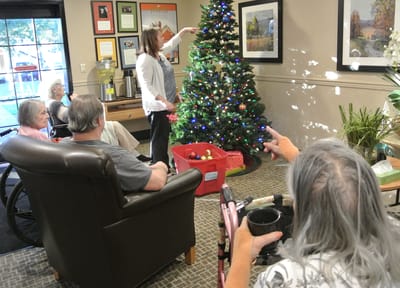 Residents decorating a Christmas tree in a common area