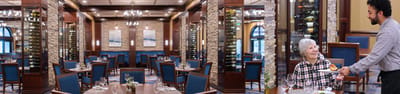 Dining room scene with a staff member serving a resident.