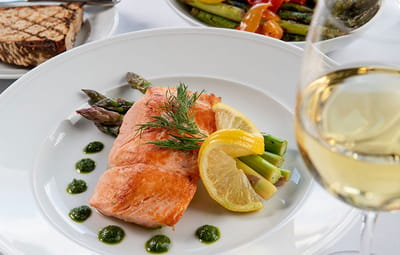 A gourmet salmon dish with vegetables and wine