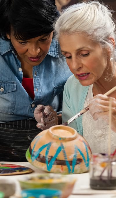 An instructor guiding a senior resident in painting activity