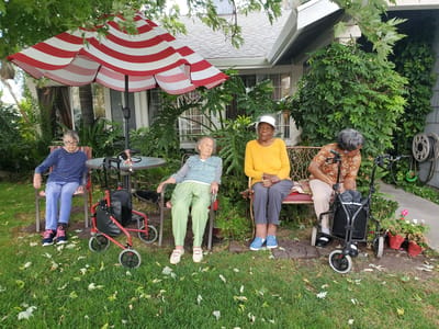 Residents enjoying time outdoors under a striped umbrella