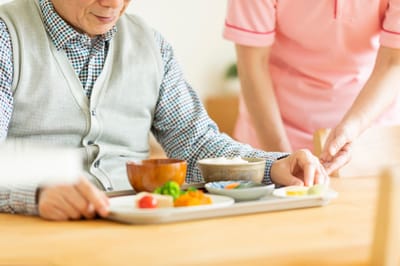 Resident enjoying a meal with staff assistance