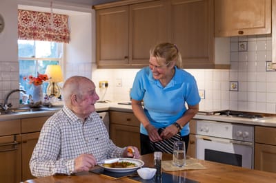 Caregiver serving food to a resident in a kitchen