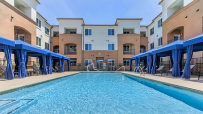 Outdoor pool area with blue cabanas near the building