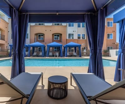 View of a pool area with cabanas and lounge chairs