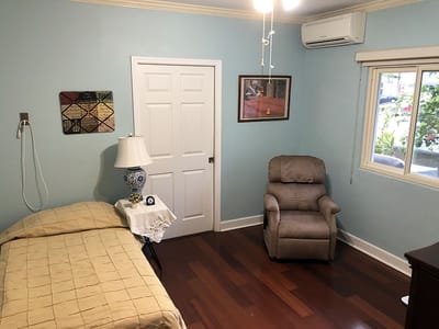 A cozy resident room with a recliner chair and bed
