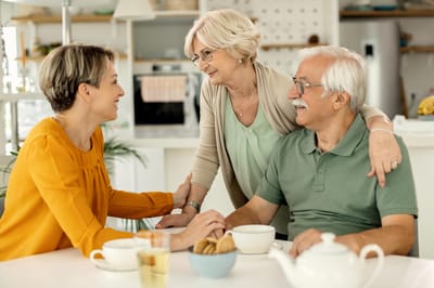 A caregiver interacting with two senior residents at a table