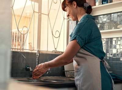 Staff member washing hands in a kitchen area