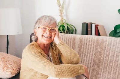A smiling senior woman sitting in a cozy living space