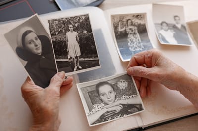 Elderly hands holding old photographs in an album