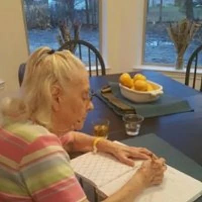 An elderly woman writing at a table