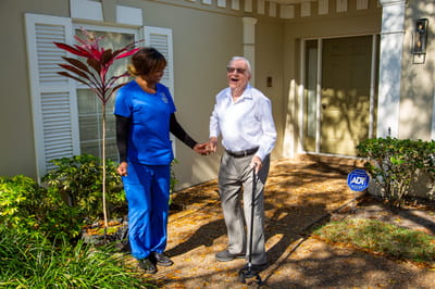 A staff member assisting a resident outside a facility entrance